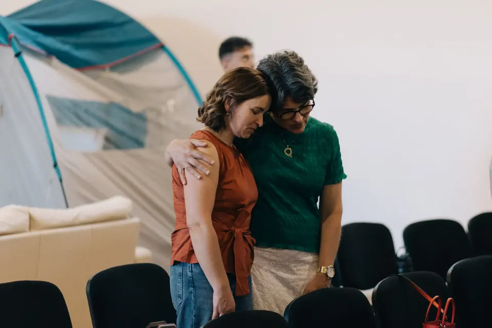 Duas mulheres abraçadas durante uma reunião